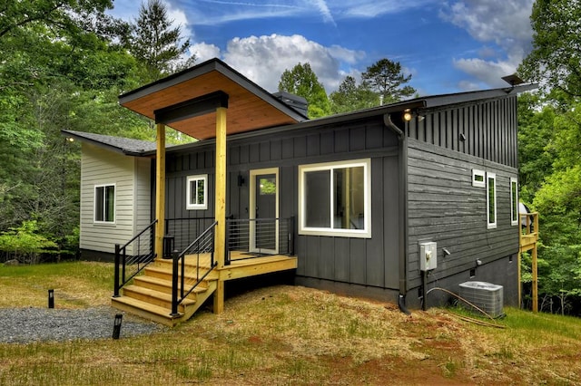 back of house with central AC unit and board and batten siding