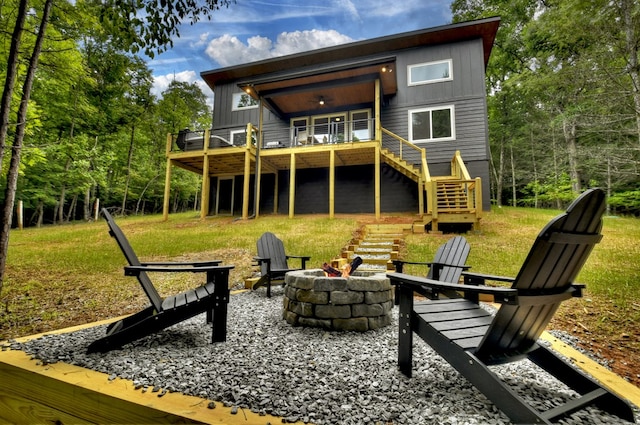 back of property featuring board and batten siding, a fire pit, stairway, a wooden deck, and a lawn