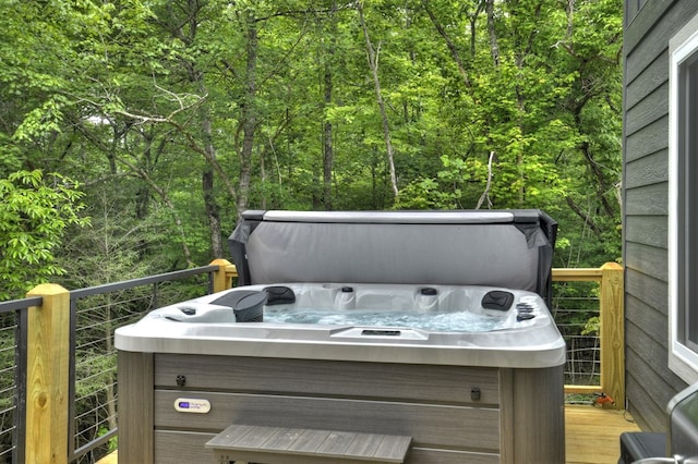 deck with a forest view and a hot tub