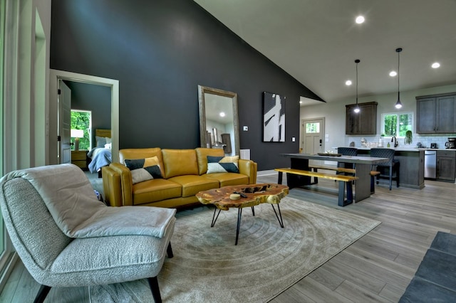 living room with recessed lighting, light wood-style floors, and high vaulted ceiling