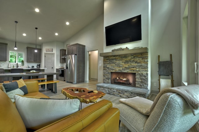 living area with light wood finished floors, recessed lighting, a fireplace, and high vaulted ceiling