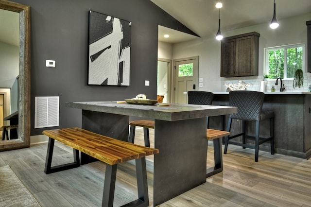 kitchen with light wood finished floors, visible vents, decorative backsplash, and dark brown cabinetry