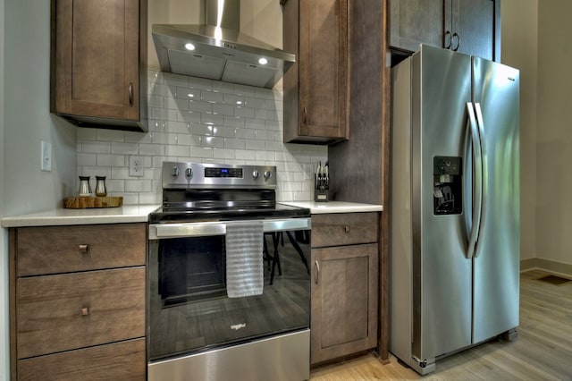 kitchen with stainless steel appliances, tasteful backsplash, visible vents, and wall chimney range hood