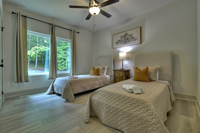 bedroom with baseboards, light wood-style floors, and ceiling fan