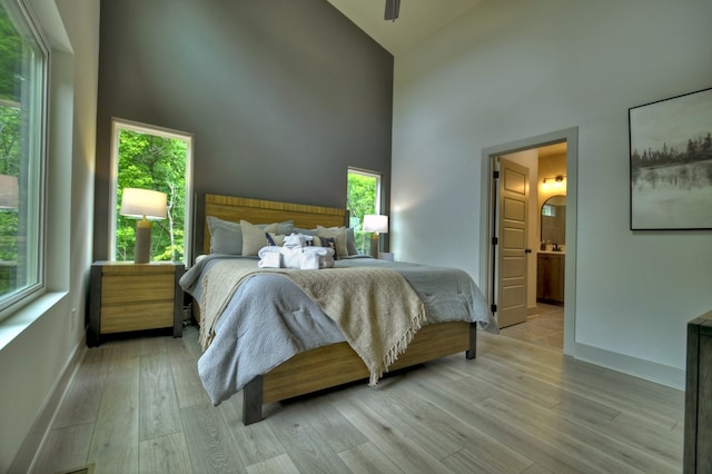 bedroom with multiple windows, high vaulted ceiling, and light wood finished floors