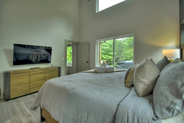 bedroom with light wood-style floors and a towering ceiling