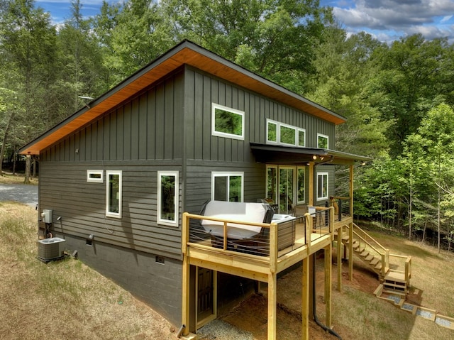 rear view of house featuring an outdoor living space, central AC unit, board and batten siding, and a deck