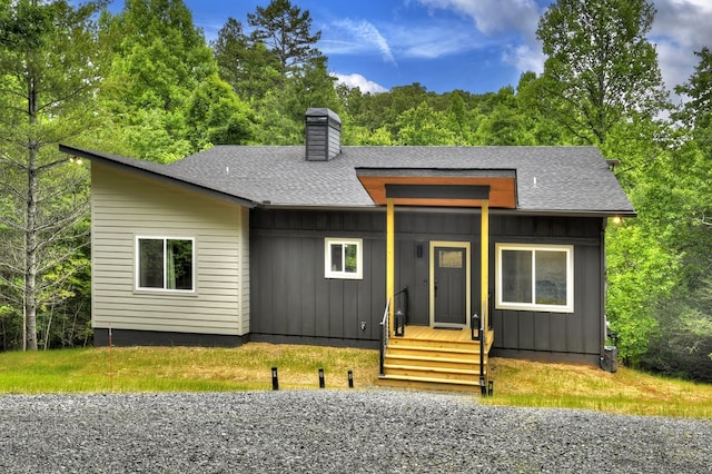 view of front of property featuring board and batten siding, roof with shingles, and a chimney