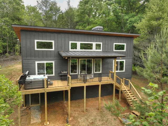 back of property with a standing seam roof, stairway, a deck, and board and batten siding