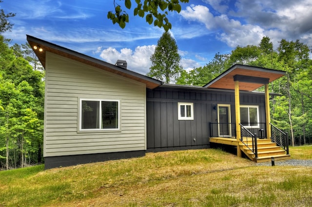 back of property with a lawn and board and batten siding