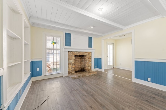 unfurnished living room featuring beamed ceiling, crown molding, a fireplace, wood ceiling, and hardwood / wood-style flooring