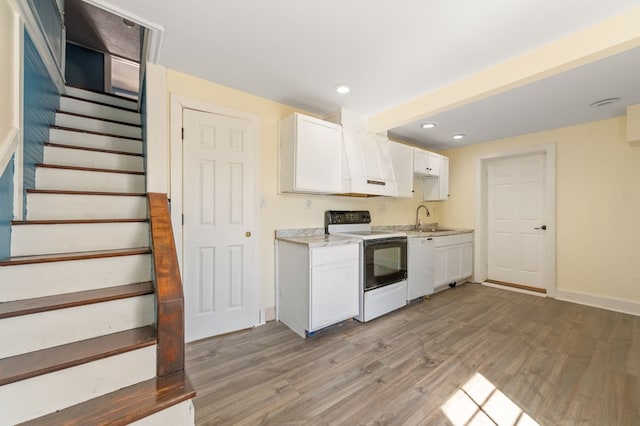 kitchen with white cabinetry, sink, light hardwood / wood-style floors, and white appliances