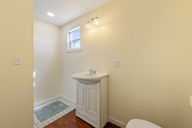 bathroom with hardwood / wood-style flooring, vanity, and toilet