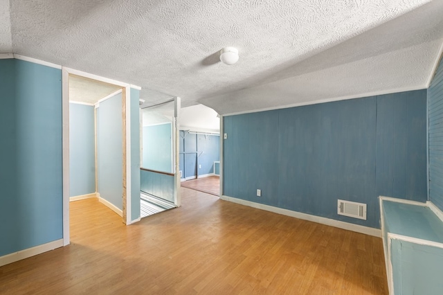 spare room with hardwood / wood-style floors, crown molding, and a textured ceiling