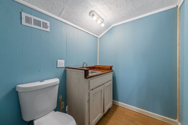 bathroom with vanity, vaulted ceiling, hardwood / wood-style flooring, toilet, and a textured ceiling