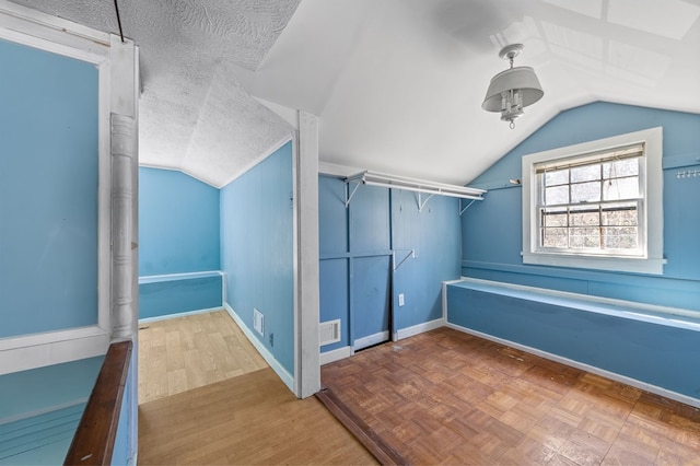 additional living space with a textured ceiling, lofted ceiling, and parquet flooring