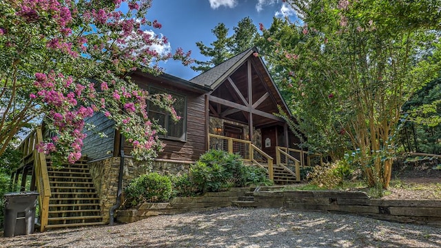 view of front of home featuring stone siding, stairs, and a porch