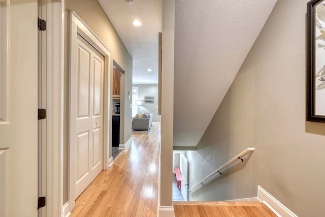 corridor with recessed lighting, an upstairs landing, baseboards, and light wood finished floors