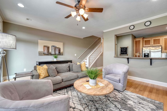 living room with light wood-type flooring, stairway, and ornamental molding