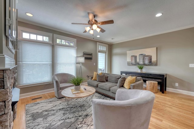 living room with crown molding, a ceiling fan, and a wealth of natural light