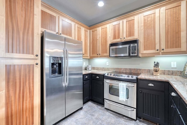 kitchen with light stone counters, stainless steel appliances, light brown cabinetry, and light tile patterned floors