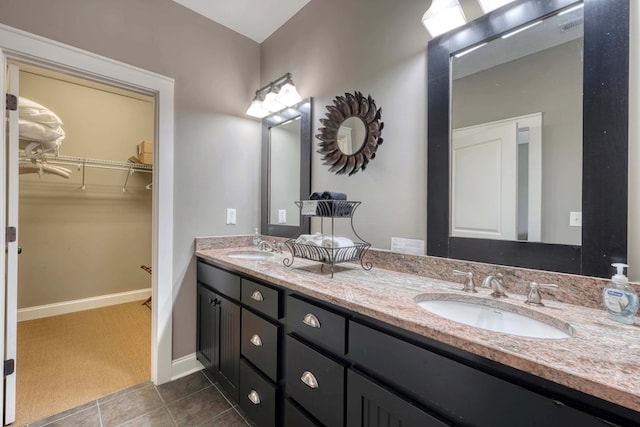 full bath featuring tile patterned flooring, double vanity, a walk in closet, and a sink