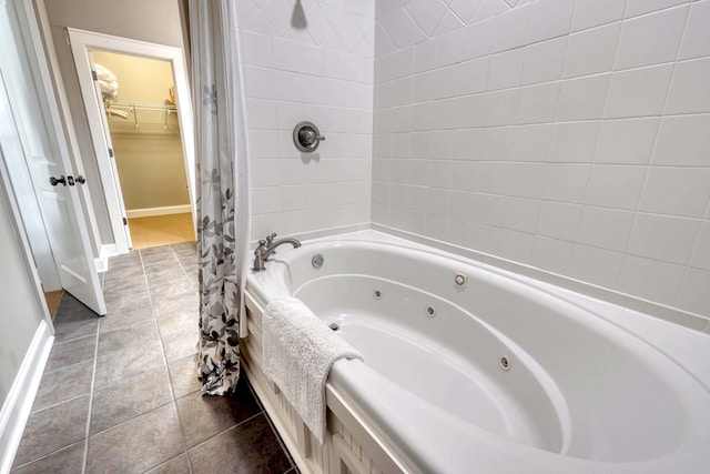 full bath featuring tile patterned flooring, a walk in closet, a combined bath / shower with jetted tub, and baseboards