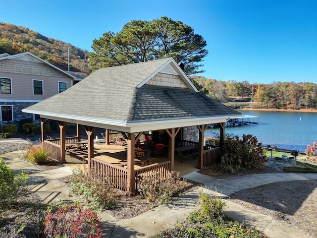 exterior space with a gazebo, a water view, and a shingled roof