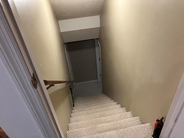 stairs featuring carpet and a textured ceiling