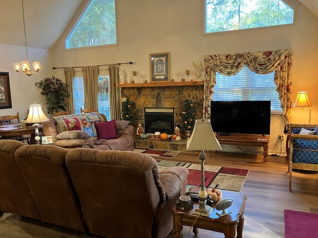 living room featuring a stone fireplace, hardwood / wood-style flooring, high vaulted ceiling, and a chandelier