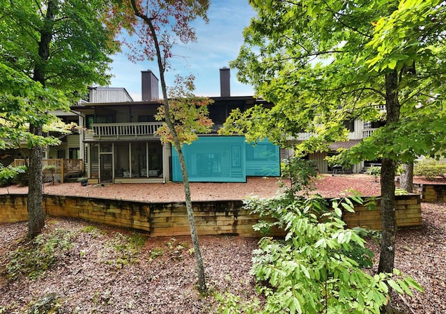 rear view of house featuring a chimney and a sunroom