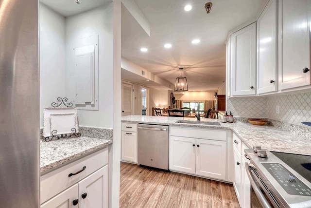 kitchen featuring white cabinets, light wood-style flooring, tasteful backsplash, appliances with stainless steel finishes, and a sink
