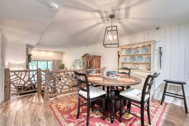 dining space with an inviting chandelier, light wood-type flooring, and wood walls