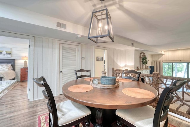 dining space with light hardwood / wood-style flooring, wood walls, and a fireplace