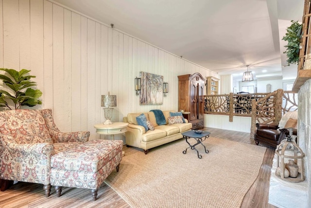 living room with a notable chandelier, wood-type flooring, and wooden walls