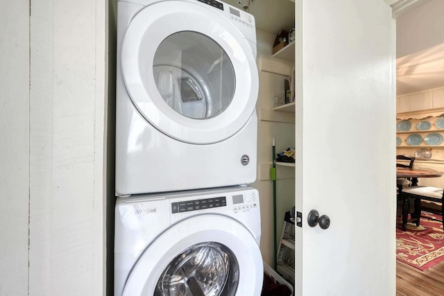 laundry area featuring stacked washer / drying machine and hardwood / wood-style floors