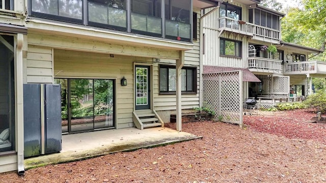 view of exterior entry with a balcony and a patio