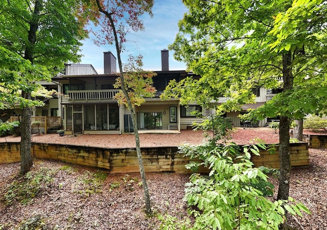 back of property featuring a sunroom and a chimney