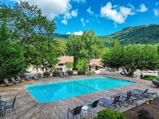 community pool featuring fence, a patio, and a mountain view
