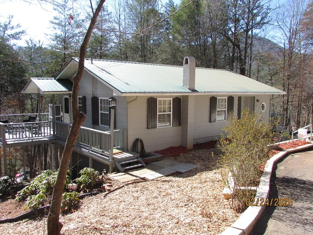 view of front facade featuring a deck, a chimney, and metal roof