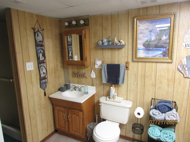 bathroom featuring visible vents, vanity, toilet, and wooden walls