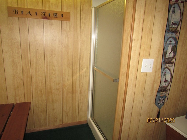 full bathroom with wood walls and a stall shower