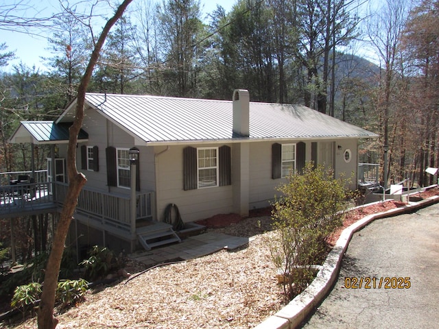 view of front of house with a standing seam roof, metal roof, a chimney, and a wooden deck