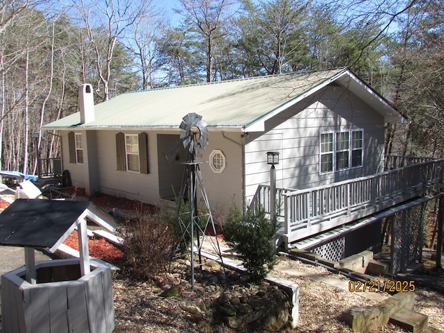 view of front facade featuring a chimney, metal roof, and a wooden deck