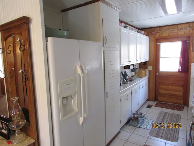 kitchen with light tile patterned floors, light countertops, white refrigerator with ice dispenser, and white cabinets