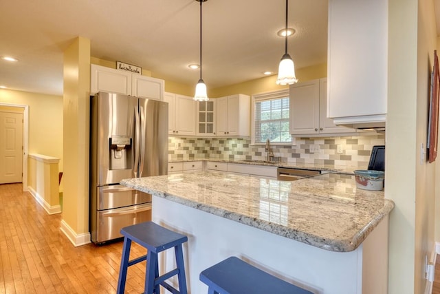 kitchen with sink, stainless steel appliances, white cabinets, decorative light fixtures, and kitchen peninsula