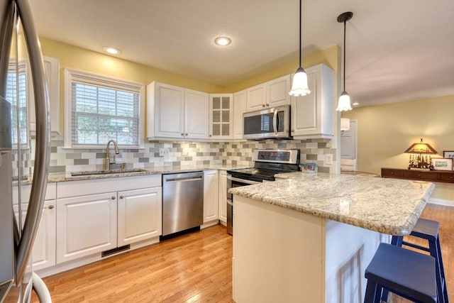 kitchen with a kitchen bar, sink, white cabinetry, kitchen peninsula, and stainless steel appliances