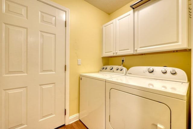 laundry area featuring separate washer and dryer, hardwood / wood-style flooring, and cabinets