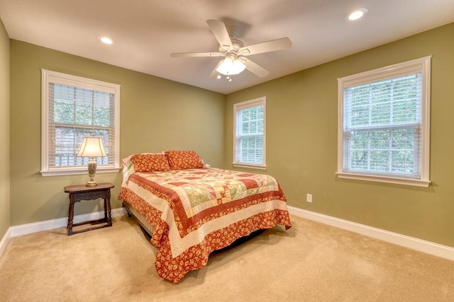 bedroom with multiple windows, light colored carpet, and ceiling fan