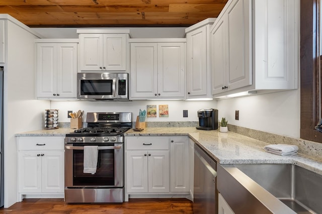 kitchen with light stone countertops, stainless steel appliances, dark wood-type flooring, wooden ceiling, and white cabinetry